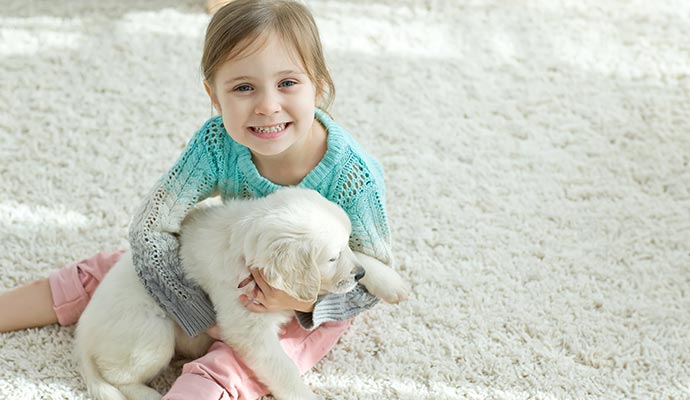 Happy child and dog sitting together on a cozy carpet.