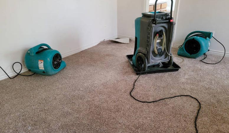 Drying out floor with dehumidifiers to prevent moisture damage.